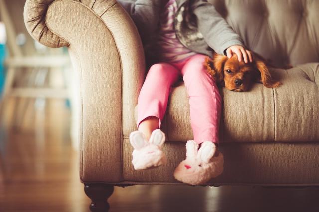 child sits on a couch next to a puppy