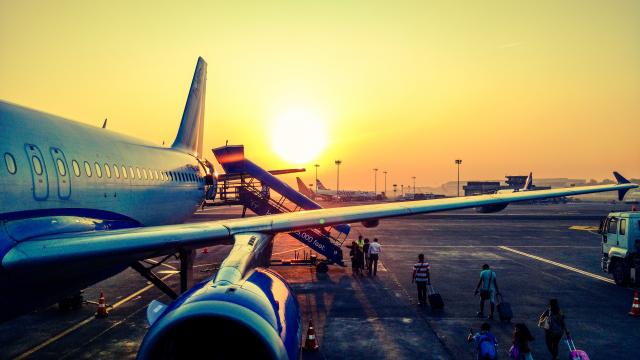 people boarding a plane at sunrise