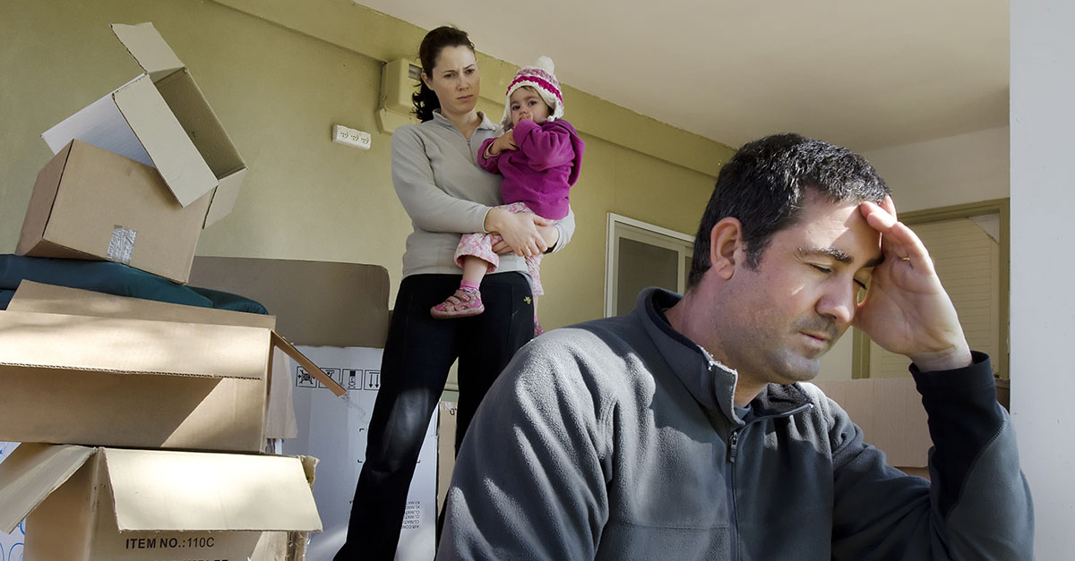 A picture of a woman, man and child, surrounded by moving boxes, looking stressed.