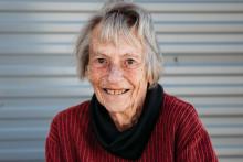 Margaret, an older woman with fair skin in front of a corrugated iron wall